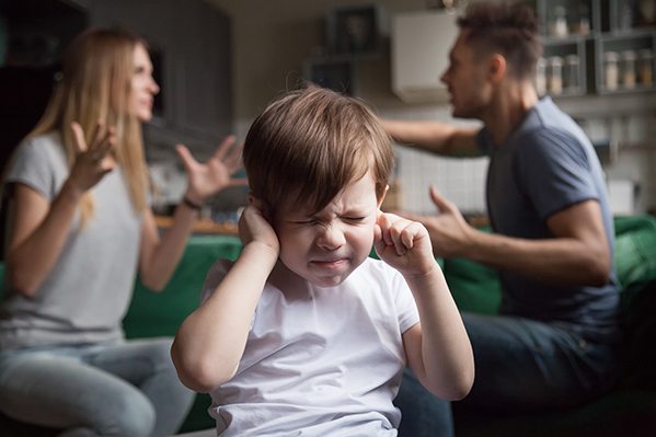 Frustrated kid son puts fingers in ears while parents arguing